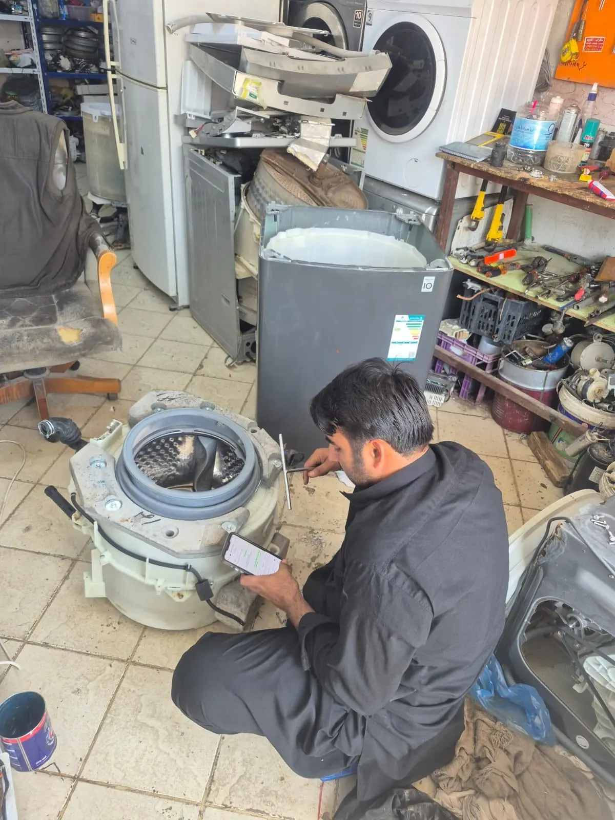 Technician working on a washing machine drum in the repair workshop